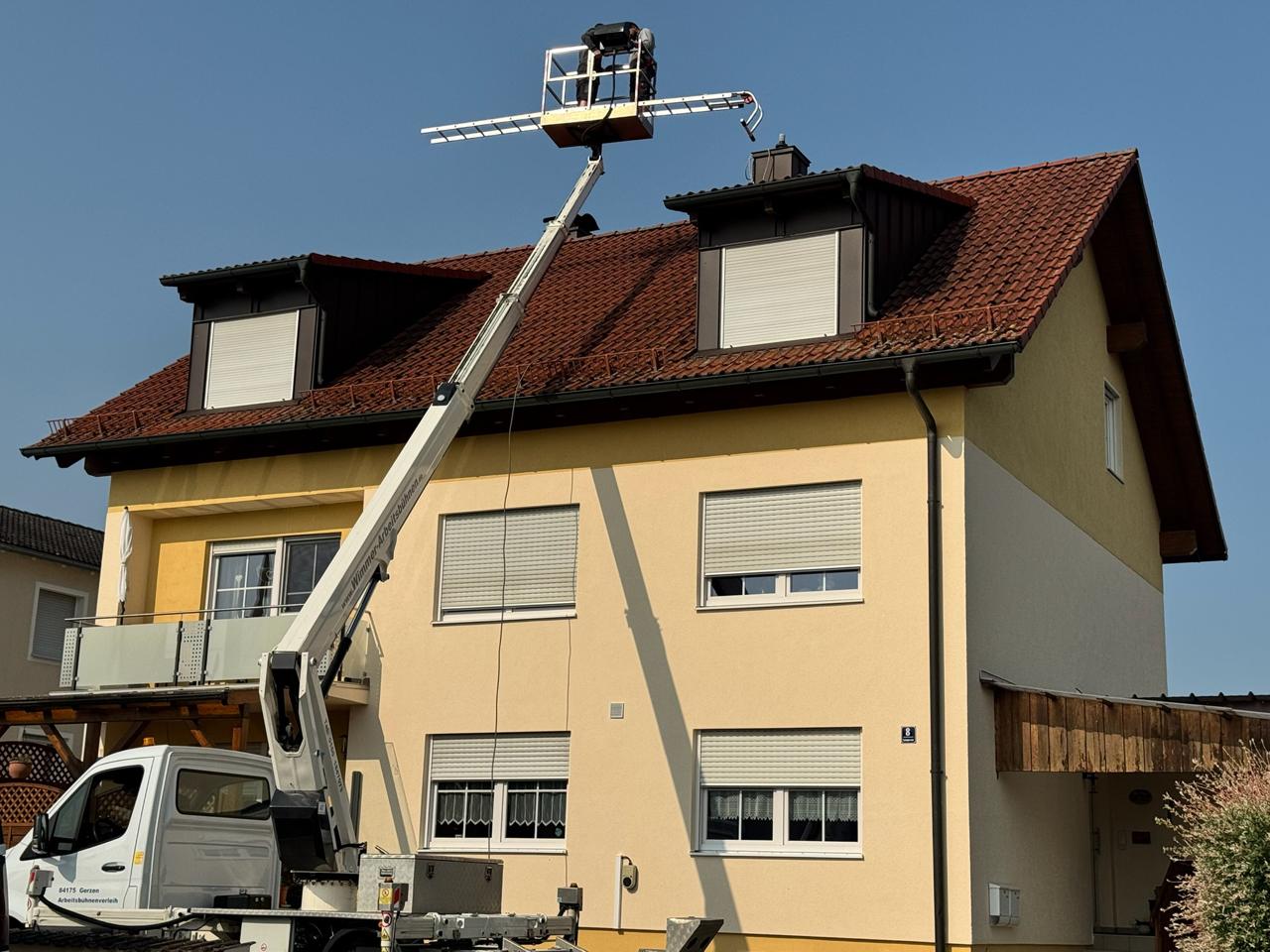 Arbeitsbühne an einem Mehrfamilienhaus zur Dachreinigung