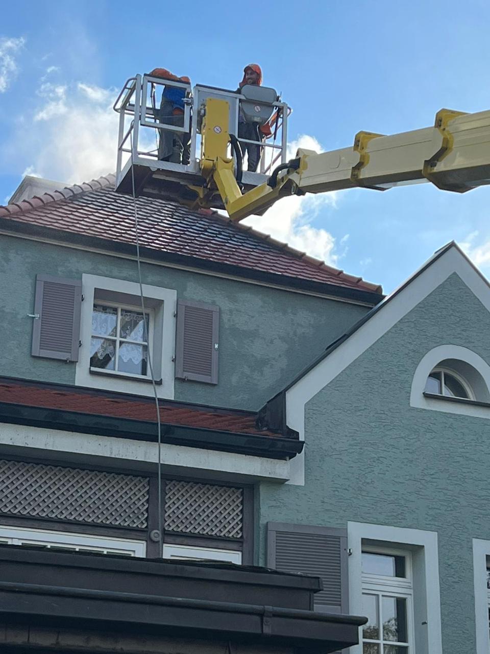 Zwei Mitarbeiter in der Arbeitsbühne über dem Dach