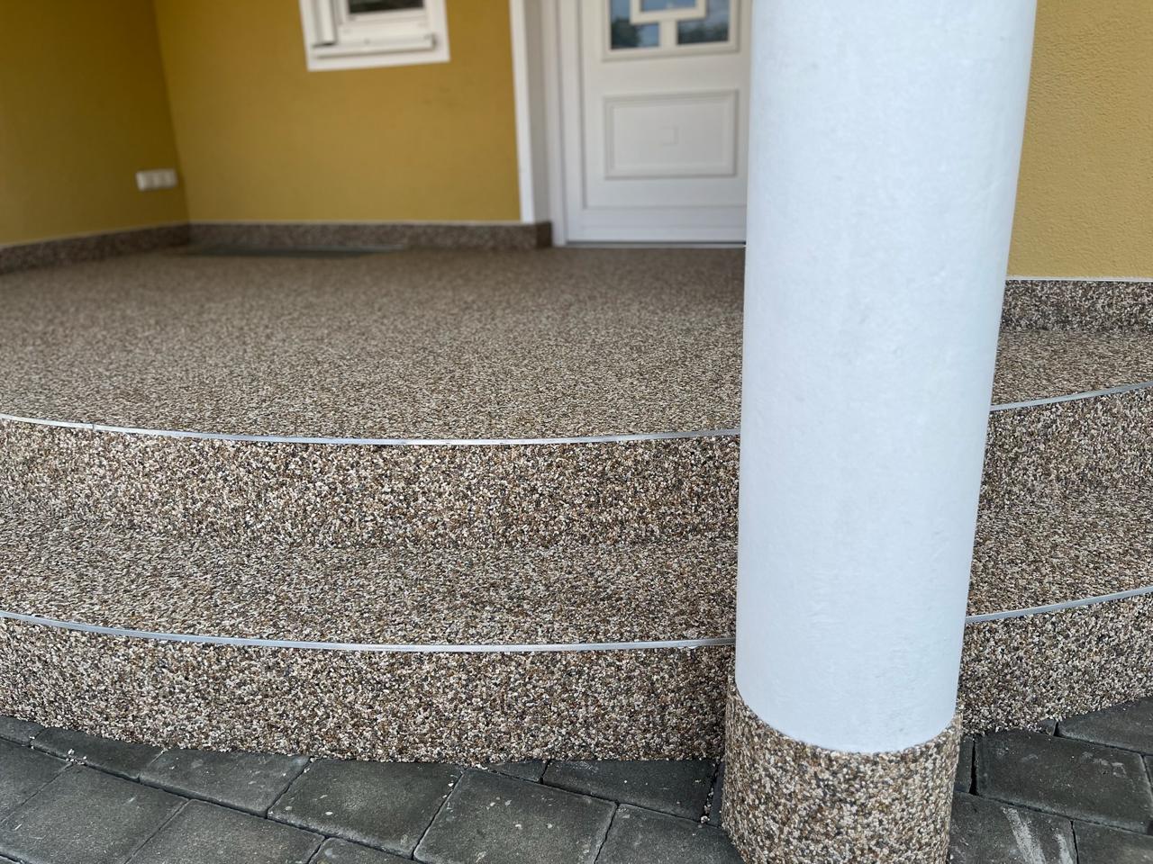 Runder Hauseingang mit Steinteppich in Braun und Edelstahlkanten