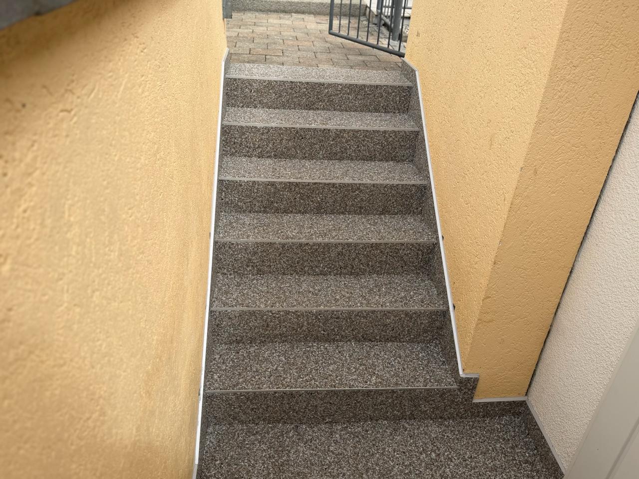 Schmale Steinteppich-Treppe zwischen zwei Hauswänden
