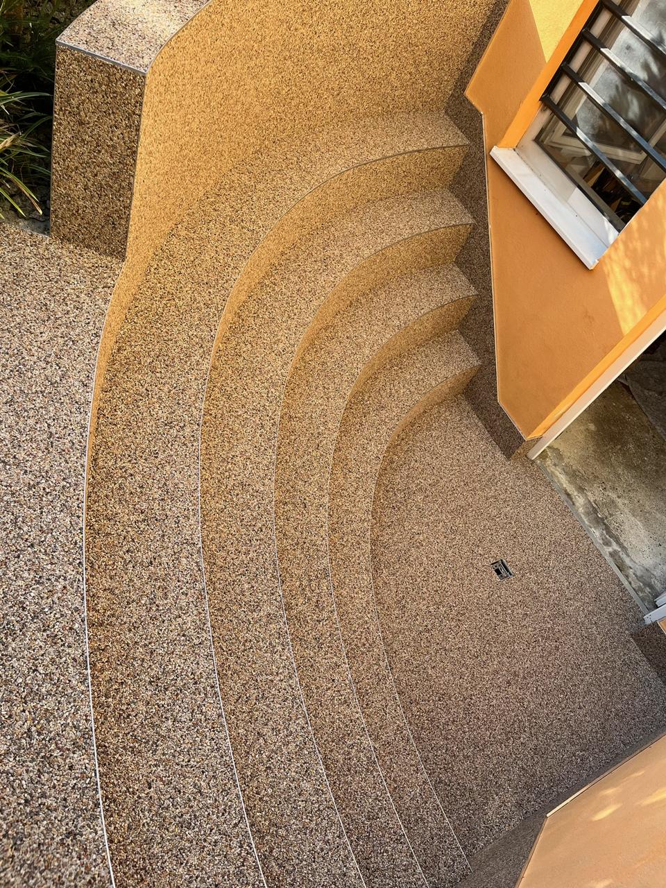 Dieselbe geschwungene Treppe nach der Steinteppich-Verlegung in warmem Braun