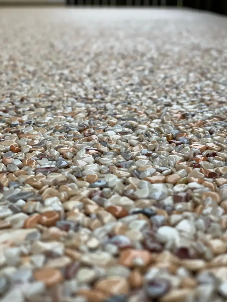Nahaufnahme frisch versiegelter Steinteppich mit glänzenden Marmorkieseln